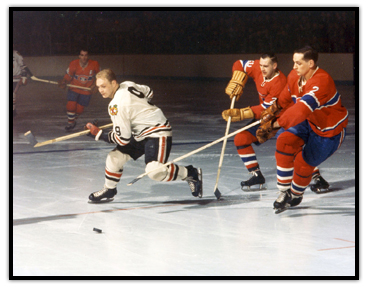 Bobby Hull skating away from two Montreal Canadiens with the puck