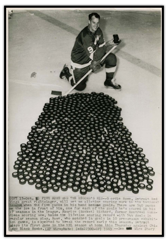 Gordie Howe posing in front of 540 pucks