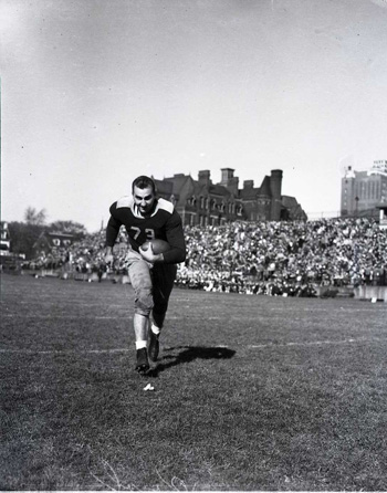 Joe Krol running with a football in his arms.